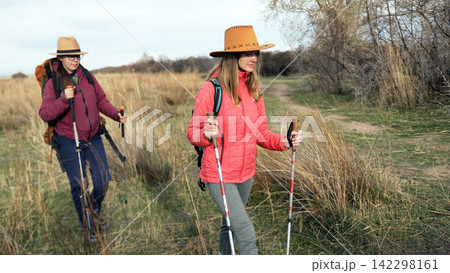 Two active young women are walking in the wilderness. The sisters travel together. Beautiful female students have opened the summer hiking season 142298161
