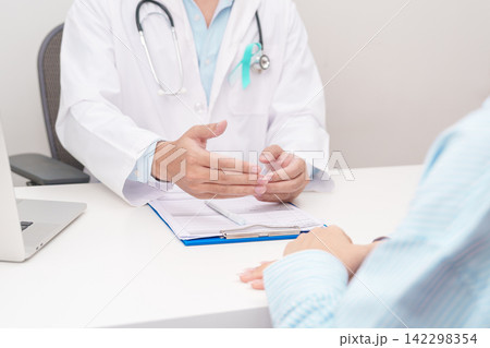 Doctor and patient having a medical consultation for Teal and white ribbon concept of January Cervical Cancer Awareness month, September Ovarian Cancer, PCOS, April Sexual Assault Doctor and patient having a medical consultation for Teal and white ribbon concept of January Cervical Cancer Awareness month, September Ovarian Cancer, PCOS, April Sexual Assault 142298354