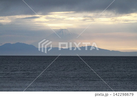 館山・北条海岸から望む雲の切れ間から光が射す夕暮れの富士山 館山・北条海岸から望む雲の切れ間から光が射す夕暮れの富士山 142298679