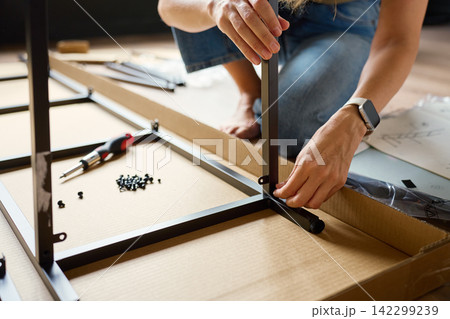 Woman assembling flat pack shelving unit at home Woman assembling flat pack shelving unit at home 142299239