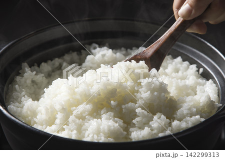 土鍋で炊いたご飯をしゃもじで混ぜるシーン 土鍋で炊いたご飯をしゃもじで混ぜるシーン 142299313