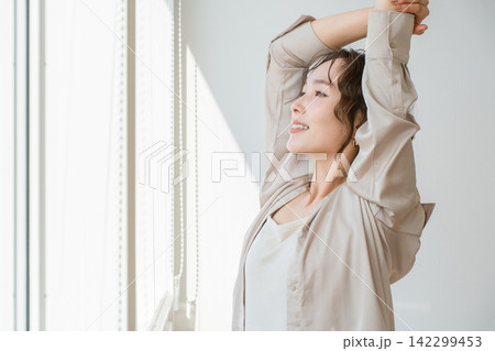 リビングの窓辺でストレッチをする美しい女性モデル 142299453