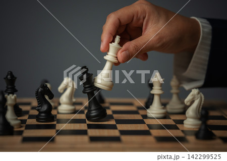business hand holding white chess king taking black king, checkmate concept business hand holding white chess king taking black king, checkmate concept 142299525