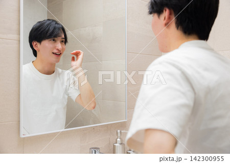 洗面所で鏡を見る若い男性 洗面所で鏡を見る若い男性 142300955