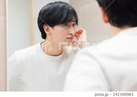 洗面所で鏡を見る若い男性 洗面所で鏡を見る若い男性 142300963