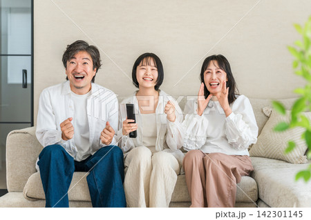 リビングのソファでテレビのリモコンを持ってくつろぐ家族,ファミリー リビングのソファでテレビのリモコンを持ってくつろぐ家族,ファミリー 142301145