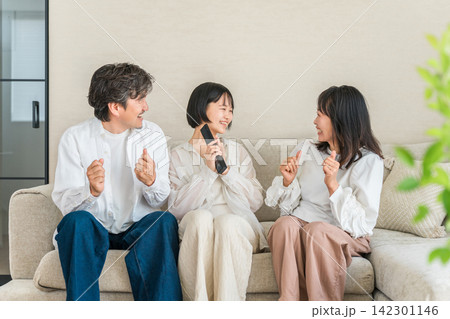 リビングのソファでテレビのリモコンを持ってくつろぐ家族,ファミリー 142301146
