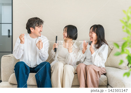 リビングのソファでテレビのリモコンを持ってくつろぐ家族,ファミリー 142301147