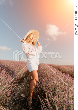 Woman lavender field wearing straw hat and white clothes standing among purple flowers under a sunny sky with copy space 142301676