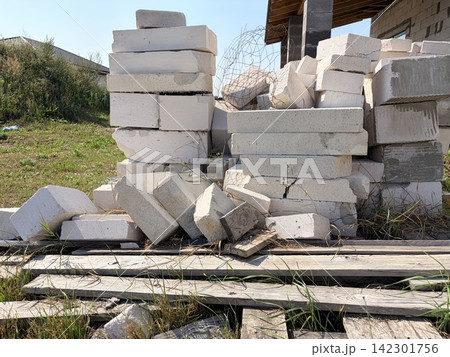 A pile of white aerated concrete blocks and construction waste on wooden pallets. 142301756