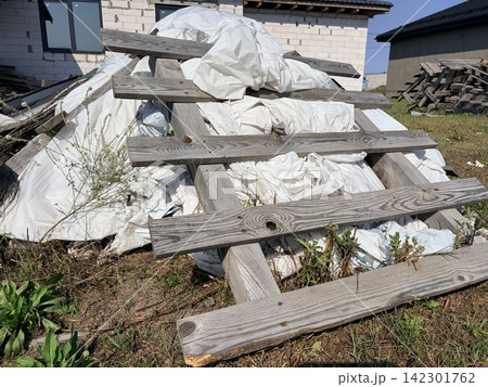 A pile of dilapidated wooden pallets and plastic waste at a construction site. 142301762