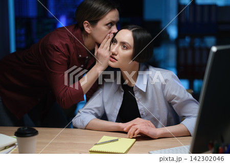 Business woman whispers private information to office colleague Business woman whispers private information to office colleague 142302046