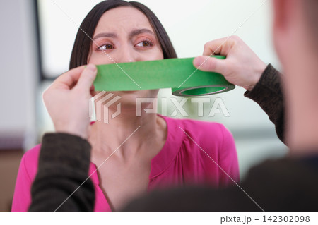 Man hands put tape over young woman mouth to kidnap indoors Man hands put tape over young woman mouth to kidnap indoors 142302098