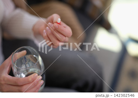 Woman holds transparent glass of fresh water and tablet in hands 142302546