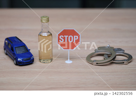 Toy car bottle of alcohol and pair of handcuffs around Stop sign Toy car bottle of alcohol and pair of handcuffs around Stop sign 142302556
