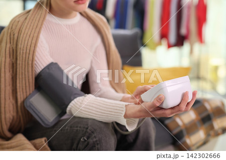 Woman checks blood pressure with digital monitor while resting Woman checks blood pressure with digital monitor while resting 142302666