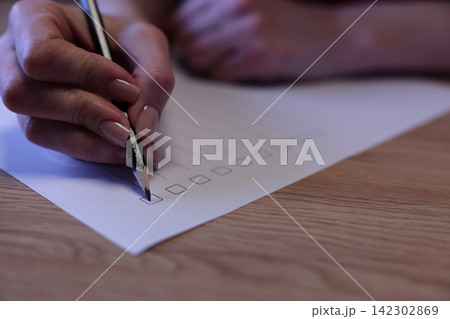 Female student hand with pencil marks answers in test list Female student hand with pencil marks answers in test list 142302869