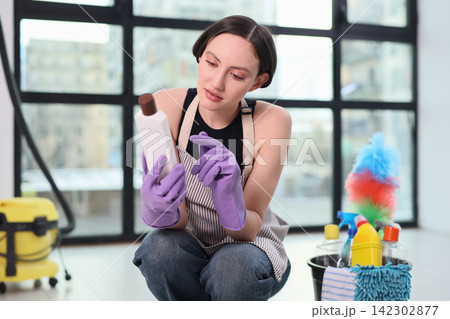 Young woman in gloves and apron reads detergent ingredients list Young woman in gloves and apron reads detergent ingredients list 142302877
