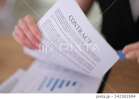 Businesswoman organizes contract pages with blue binder clip Businesswoman organizes contract pages with blue binder clip 142302894