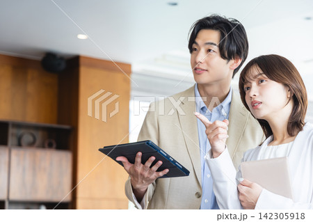 タブレットを手にして前方を見指しながら打ち合わせをするビジネスマンとビジネスウーマン 142305918