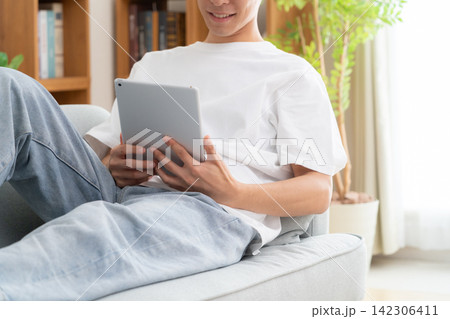 家でタブレットを見る若い男性 家でタブレットを見る若い男性 142306411