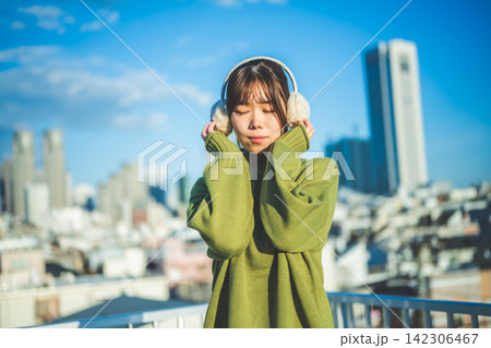 イヤマフをつけた女性、目を閉じて音楽を聴く 142306467