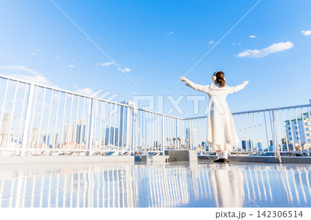 青空の下、両手を広げる白い服の女性 青空の下、両手を広げる白い服の女性 142306514