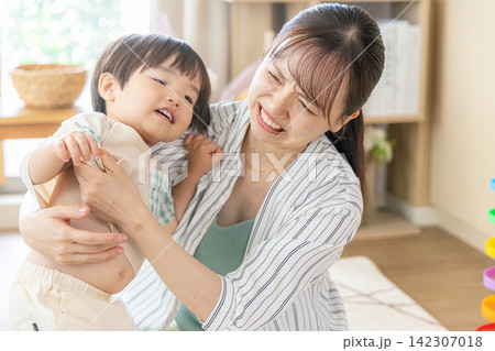 子供の着替えがうまくいかなくてイライラしている母親 142307018