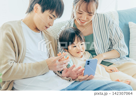 スマホで動画を見る若い家族 スマホで動画を見る若い家族 142307064