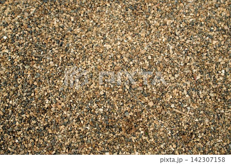 Continuous outdoor surface covered with medium-grain yellow-brown gravel mix and sand aggregate, daylight Continuous outdoor surface covered with medium-grain yellow-brown gravel mix and sand aggregate, daylight 142307158