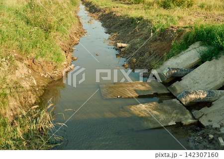 Close up shot looking at heavy sewage infrastructure pipes dumping liquid waste Close up shot looking at heavy sewage infrastructure pipes dumping liquid waste 142307160