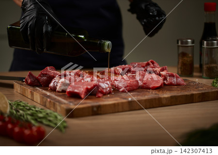 Chef pouring olive oil on raw beef steak 142307413