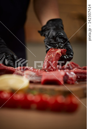 Preparing raw meat with seasoning for cooking Preparing raw meat with seasoning for cooking 142307414