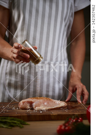 Chef seasoning raw chicken breast with spices 142307462