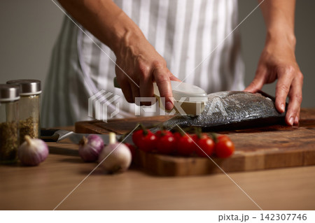 Chef scaling fresh gilthead sea bream for cooking Chef scaling fresh gilthead sea bream for cooking 142307746