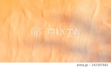 Warm orange peach textured plaster wall featuring rough stucco surface covered by dark soft cast shadows providing beautiful blank background layout completely 142307882