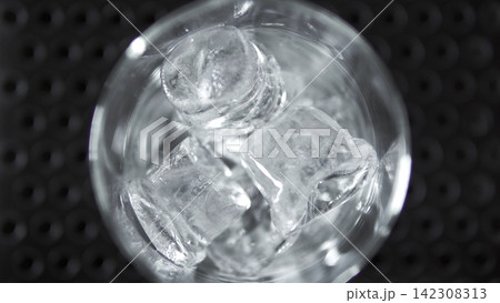 Clear glass with melting ice cubes, offering refreshing, chilled beverage for summer drinks and cocktail preparation Clear glass with melting ice cubes, offering refreshing, chilled beverage for summer drinks and cocktail preparation 142308313
