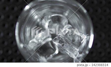Glass of water with ice cubes, refreshing chilled beverage, overhead view illustrating coldness and purity Glass of water with ice cubes, refreshing chilled beverage, overhead view illustrating coldness and purity 142308314