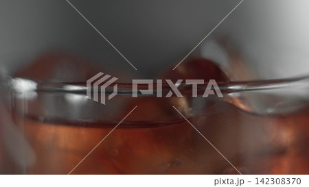 Cold glass filled with ice cubes and refreshing red beverage, creating transparency and liquid dynamics 142308370