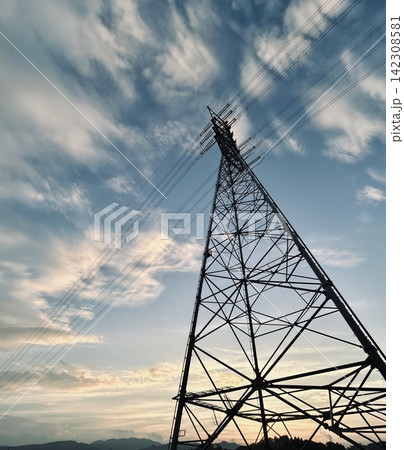 夕空を背景にそびえる送電鉄塔と電線 142308581