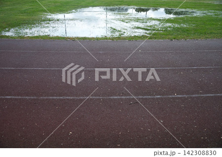Athletics track after heavy rain with flooded grass, making outdoor training difficult in autumn Athletics track after heavy rain with flooded grass, making outdoor training difficult in autumn 142308830
