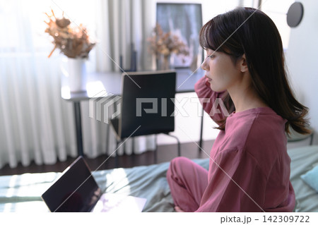 ベッドでノートパソコンを操作する女性 ベッドでノートパソコンを操作する女性 142309722