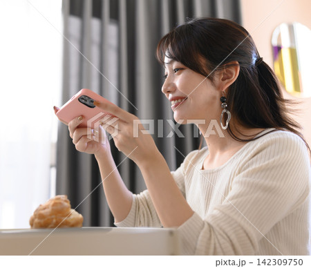 スマホを持つ笑顔の女性 142309750