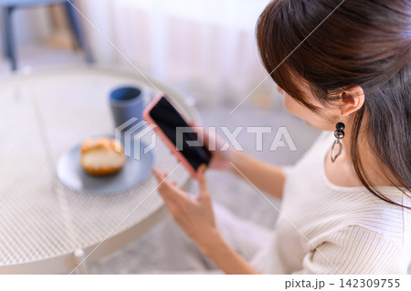 スマートフォンでスイーツを撮影する女性の日常風景 スマートフォンでスイーツを撮影する女性の日常風景 142309755