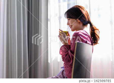窓辺で飲み物を飲む女性 窓辺で飲み物を飲む女性 142309785