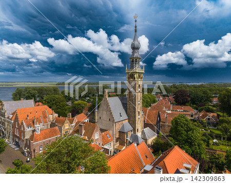 High angle wide horizontal aerial drone photograph of Veere City Hall tower, historic orange roofs, Lake Veere, and dramatic storm sky in Veere, Zeeland, Netherlands on summer day High angle wide horizontal aerial drone photograph of Veere City Hall tower, historic orange roofs, Lake Veere, and dramatic storm sky in Veere, Zeeland, Netherlands on summer day 142309863