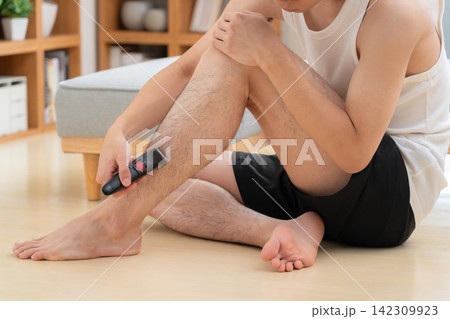 家で脚の脱毛をする若い男性 家で脚の脱毛をする若い男性 142309923