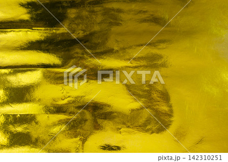 Abstract background of a shiny golden metallic foil texture with reflective crinkled patterns and bright yellow highlights. Holiday, celebration or texture background Abstract background of a shiny golden metallic foil texture with reflective crinkled patterns and bright yellow highlights. Holiday, celebration or texture background 142310251