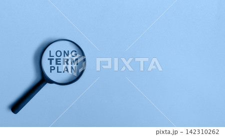 Magnifying glass highlighting the words "LONG TERM PLAN" on a blue background. Minimalist business strategy concept with copy space. Concept of Planning Magnifying glass highlighting the words "LONG TERM PLAN" on a blue background. Minimalist business strategy concept with copy space. Concept of Planning 142310262