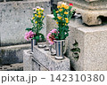 墓石に供えられた色鮮やかな花と金属製の花立て 142310380